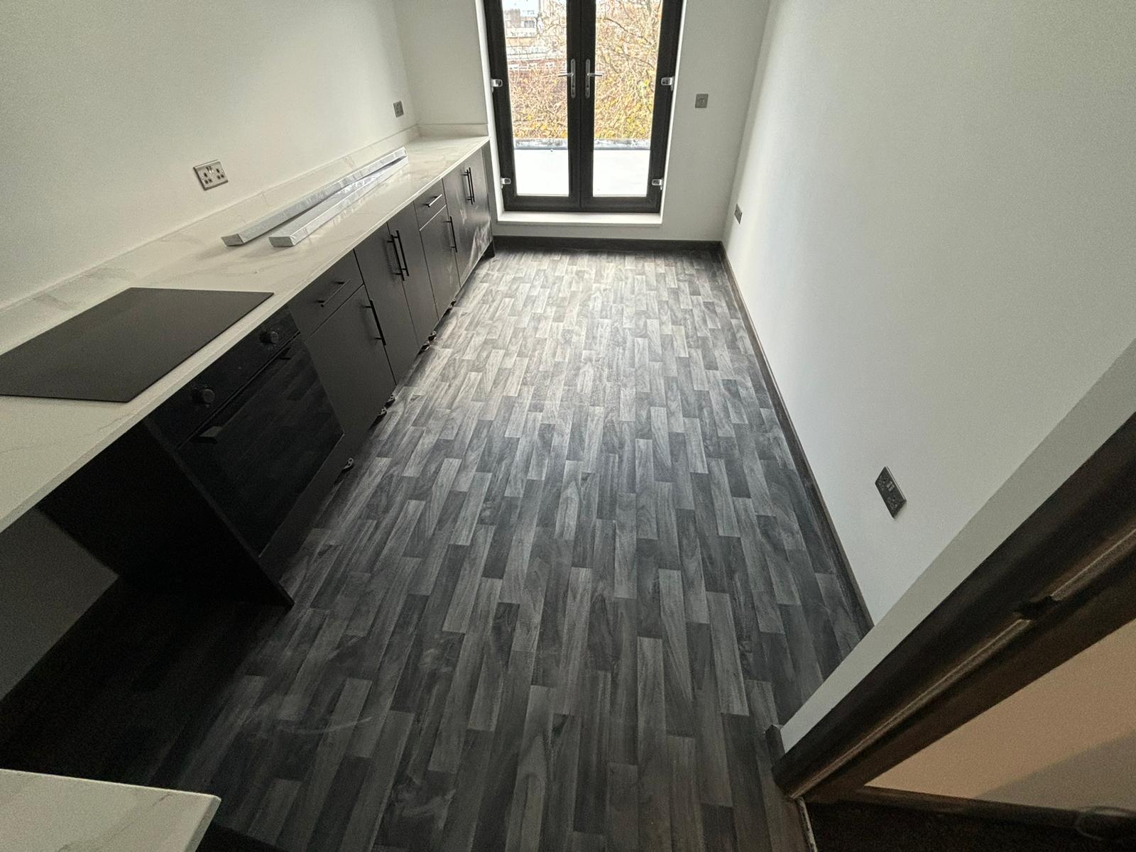 Grey wood-effect flooring in a kitchen with dark cabinets